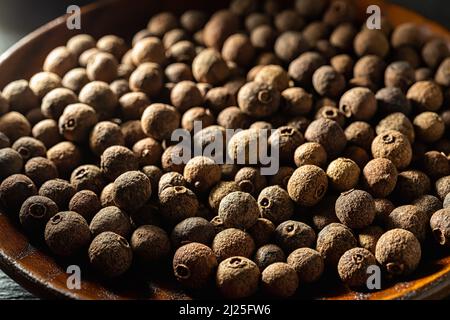 Gros plan de grains de poivre de jamaïque d'épices brunes en plein soleil. Texture de baies entières de piment séché. Concepts d'épices biologiques, assaisonnement Banque D'Images