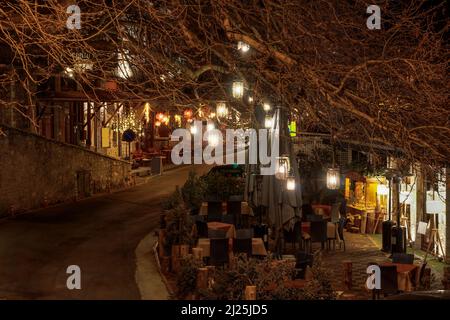 Café extérieur et taverne grecque coin salon sous de grandes branches d'arbres sur une rue de nuit vide à Lagadia, Arcadia Péloponnese Banque D'Images