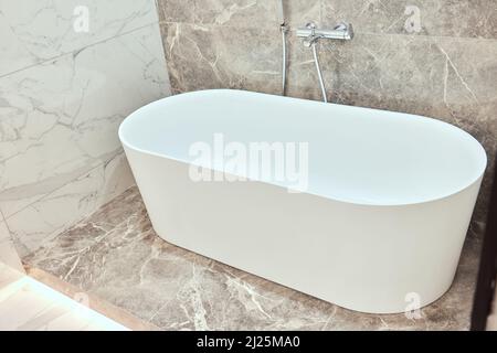 Grande baignoire ovale de luxe dans la salle de bains avec carrelage en marbre noir et blanc sur les murs et le sol Banque D'Images