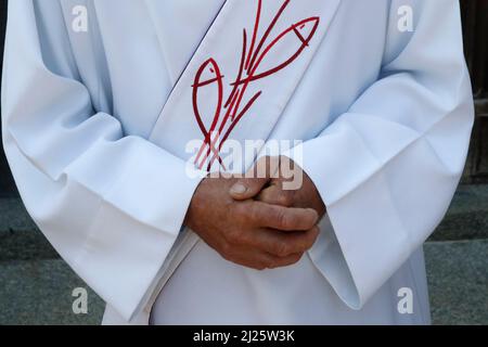 Église catholique. Diacre. Gros plan sur le chasuble et les mains. Banque D'Images