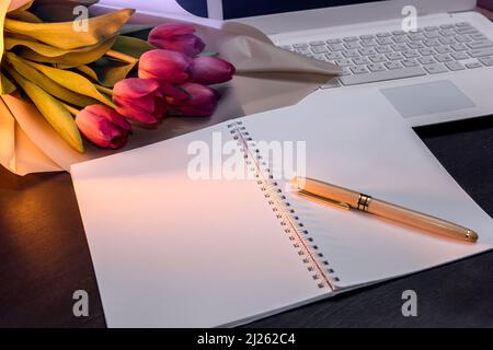 Bloc-notes avec bouquet de tulipes sur fond sombre Banque D'Images