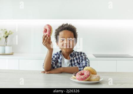 Petit garçon mangeant un beignet Banque D'Images