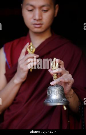 Monastère de Pema Osel Ling. Moine bouddhiste dans une robe de lama. Le moine possède les attributs rituels du bouddhisme, du rosaire, du vajra, de la cloche. Banque D'Images