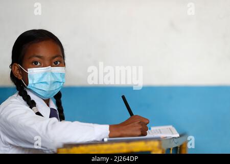 École secondaire. Fille portant un masque chirurgical en classe. Banque D'Images