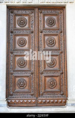 Anciennes portes en bois massif ornées de décorations sculptées à la main par des artistes locaux, dans le splendide centre historique de Lucques Banque D'Images