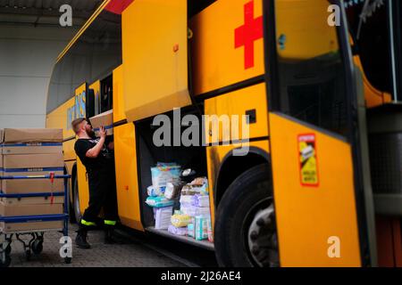 Une garde charge les fournitures d'aide dans un bus appartenant au volontaire britannique Cliff Wilson qui les transportera de Przemysl en Pologne à l'Ukraine et, à son retour, ramasse les femmes et les enfants ukrainiens et les ramasse à la frontière en Pologne. Date de la photo: Mercredi 30 mars 2022. Banque D'Images