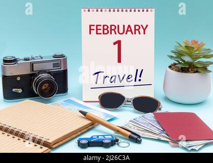 1st jour de février. Planification de voyage, voyage de vacances - Calendrier avec la date 1 février lunettes bloc-notes stylo appareil photo passeports en espèces. Mois d'hiver, jour o Banque D'Images