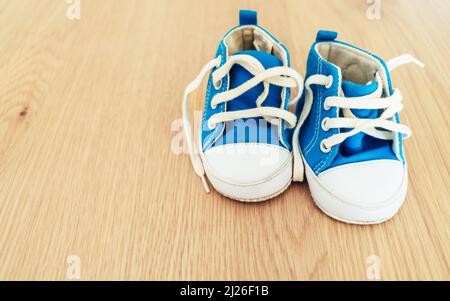 Paire de sneakers bleues et blanches pour bébé sur fond en bois. Banque D'Images