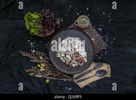 Calmars frais grillés, tentacules d'Octopus et œufs de calmars sur une assiette en céramique, servis avec des légumes frais et une sauce piquante aux fruits de mer. Vue de dessus, Sélectionner Banque D'Images