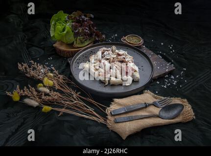 Calmars frais grillés, tentacules d'Octopus et œufs de calmars sur une assiette en céramique, servis avec des légumes frais et une sauce piquante aux fruits de mer. Mise au point sélective. Banque D'Images