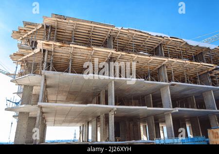 Boîte en béton du bâtiment en construction. Le gratte-ciel est construit avant les murs de maçonnerie et les ouvertures. Colonnes et sols en béton. Clôtures en bois et Banque D'Images