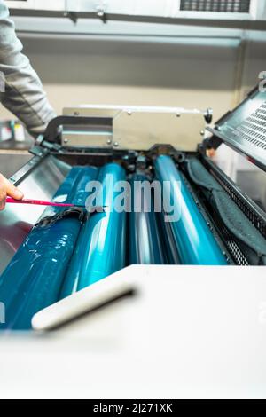 Rouleaux couleur et brillant de la machine d'impression offset. Couleur de l'encre offset. Bleu. Photo prise verticalement, cylindre de mise au point sélectionné au milieu. Banque D'Images
