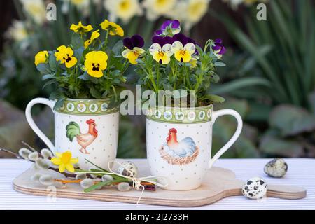 fleurs de violons jaunes et violettes en tasses avec ornement de pâques comme décoration de pâques Banque D'Images