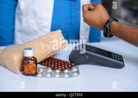 Gros plan sur l'achat de médicaments par les clients en payant de l'argent en appuyant sur la montre intelligente sur la machine à glisser dans un magasin pharmaceutique - concept de transaction sans fil Banque D'Images