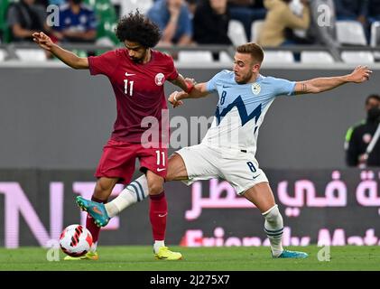 DOHA, le 30 mars 2022 (Xinhua) -- Akram Hassan Afif (L) du Qatar vies pour le bal avec Sandi Lovric de Slovénie lors d'un match international de football amical entre le Qatar et la Slovénie au stade de la ville d'éducation à Doha, Qatar, le 29 mars 2022. (Xinhua) Banque D'Images