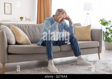 Homme mature stressé assis sur la tête de la table Banque D'Images