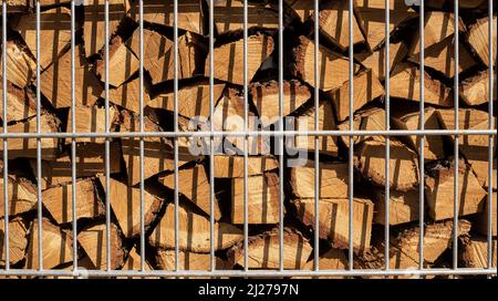 couper les bûches de bois de chauffage stockées derrière une clôture en métal Banque D'Images