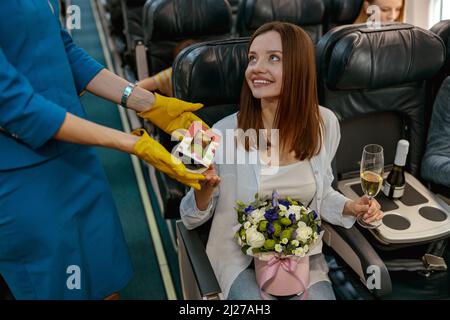 Femme joyeuse recevant des cookies de l'hôtesse en avion Banque D'Images