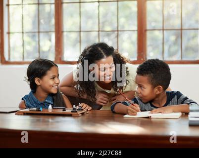 Comment allez-vous ? Photo courte d'une jeune mère attrayante aidant ses enfants à faire leurs devoirs. Banque D'Images