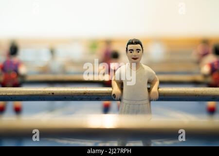 Un joueur de football de table a montré se détendre contre le bar auquel il est attaché. Le joueur a un kit de style rétro tout blanc Banque D'Images