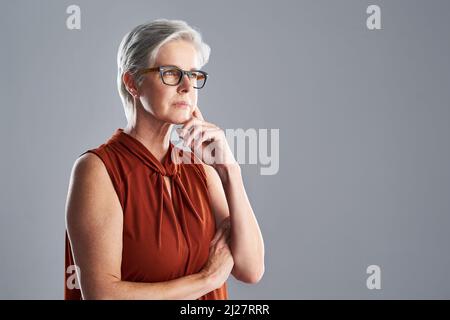 Rêvez grand ou ne rêvez pas du tout. Photo d'une femme mûre et attirante qui a l'air très réfléchie sur un fond gris. Banque D'Images