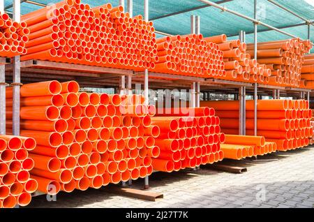 Cheminée de tuyaux d'eau en pvc orange dans une zone industrielle abandonnée - concept de construction avec pile d'équipement en plastique sur le chantier Banque D'Images