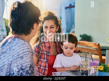 Rattraper. Photo courte d'une jeune femme attrayante et de son fils en visite avec sa mère mature. Banque D'Images