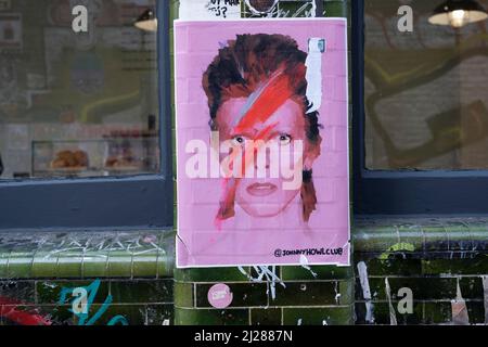 David Bowie Ziggy Stardust a collé l'art de la rue sur Brick Lane le 24th mars 2022 à East London, Royaume-Uni. Brick Lane est une rue dans le quartier est de Tower Hamlets qui va de Bethnal Green à travers Spitalfields jusqu'à Whitechapel. Aujourd'hui, c'est le coeur de la communauté bangladeshi du pays avec le voisinage connu de certains comme Banglatown. Brick Lane est connu comme un centre pour les personnes créatives et les arts, en particulier l'art de rue et l'art du graffiti, ainsi que de nombreux restaurants bangladeshi / indiens, connus sous le nom de curry maisons. Banque D'Images