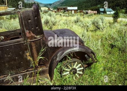 Mt: Jefferson County, Boulder Valley, Elkhorn. Ville fantôme dans un canyon, vue sur une voiture ancienne abandonnée avec roues à rayons de bois] Banque D'Images