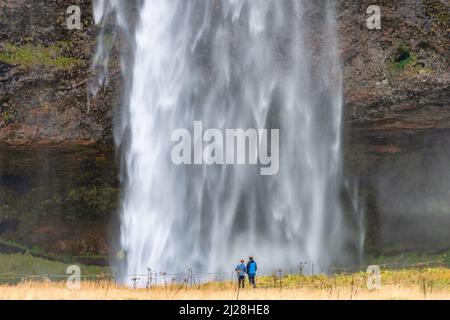 Un couple admirant l'emblématique chute d'eau de Seljalandsfoss, dans le sud de l'Islande Banque D'Images