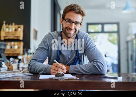 Travailler dur est payant. Une photo courte d'un beau jeune propriétaire de café faisant quelques formalités administratives. Banque D'Images