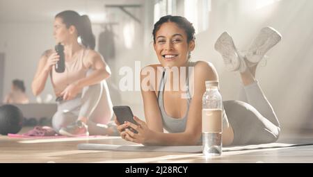 Mon entraîneur personnel virtuel me donne toute l'aide dont j'ai besoin. Photo de deux jeunes athlètes féminins qui prennent une pause pendant leur séjour à la salle de gym. Banque D'Images