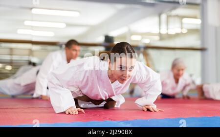 Jeune femme dans un kimono faisant des push-up dans la salle de gym Banque D'Images