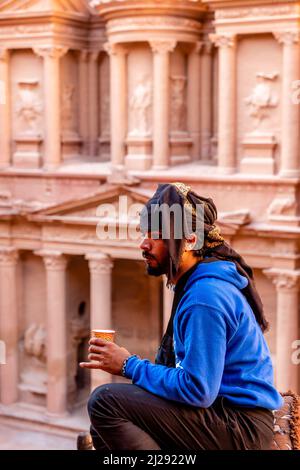 Un guide bédouin local assis en buvant du café Ovelooking l'extérieur du Trésor "Al-Khazneh", d'Un point de vue élevé, Petra, Jordanie, Asie. Banque D'Images