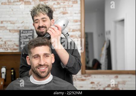 Coiffeur séchage des cheveux du client. Photo de haute qualité Banque D'Images