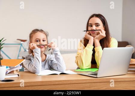 Petite fille avec tuteur ayant du plaisir pendant l'étude à la maison Banque D'Images