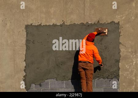 Ouvrier de construction répare un mur extérieur à Lancaster PA Banque D'Images