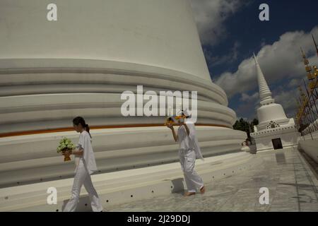 Les pèlerins portent l'offrande, alors qu'ils entourent un stupa blanc géant à Wat Phra Mahathat Woramahawihan, le principal stupa bouddhiste de Nakhon si Thammarat, la plus grande province du sud de la Thaïlande. Banque D'Images