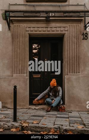 Jeune femme est assise près du beau vieux bâtiment avec chat en saison d'automne Banque D'Images