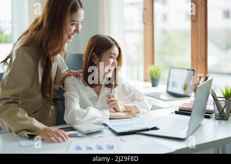 Deux femmes assis au bureau se sentent euphoriques gagner loterie en ligne, heureuse femme asiatique overjoyed obtenir le courrier à l'ordinateur portable étant promu au travail, fille biracial stupéfait Banque D'Images