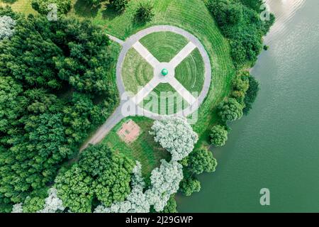 vue aérienne d'un drone volant d'un parc de la ville avec chemin de marche parmi les arbres verts en journée ensoleillée Banque D'Images