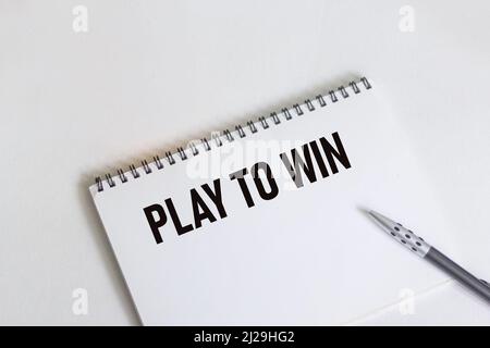 Play to Win écrit sur un ordinateur portable avec un stylo sur fond blanc Banque D'Images