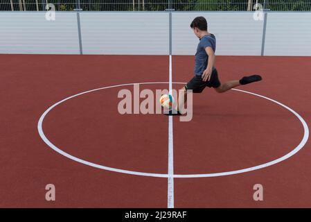 Garçon fait une balle dans une cage de football, Bavière, Allemagne Banque D'Images