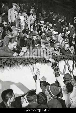 Le chancelier de Reich Adolf Hitler signe des autographes pour les athlètes canadiens dans le stade de glace artificielle, avec le ministre de la propagande de Reich Joseph Goebbels Banque D'Images