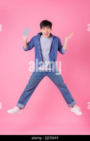 Jeune homme asiatique sautant sur fond bleu Banque D'Images