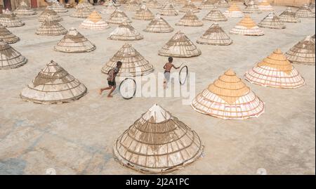 Brahmanbaria, Chittagong, Bangladesh. 31st mars 2022. Les enfants courent et jouent parmi des centaines de moulins à riz traditionnels faits de bambou.après avoir été bouilli, le grain est balayé en tas par les travailleurs et séché jusqu'à huit heures à Brahmanbaria, au Bangladesh. Le travailleur du moulin à riz a commencé son travail dès le début de la matinée, de 5 heures à 2pm heures tous les jours. Après la période du déjeuner, les enfants des travailleurs jouent leurs jeux de l'après-midi avec des amis dans ce champ de moulin à riz. (Credit image: © Mustasinur Rahman Alvi/ZUMA Press Wire) Credit: ZUMA Press, Inc./Alamy Live News Banque D'Images