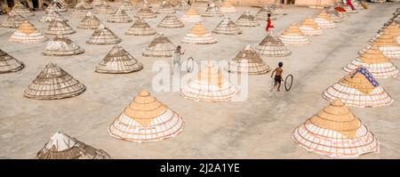 Brahmanbaria, Chittagong, Bangladesh. 31st mars 2022. Les enfants courent et jouent parmi des centaines de moulins à riz traditionnels faits de bambou.après avoir été bouilli, le grain est balayé en tas par les travailleurs et séché jusqu'à huit heures à Brahmanbaria, au Bangladesh. Le travailleur du moulin à riz a commencé son travail dès le début de la matinée, de 5 heures à 2pm heures tous les jours. Après la période du déjeuner, les enfants des travailleurs jouent leurs jeux de l'après-midi avec des amis dans ce champ de moulin à riz. (Credit image: © Mustasinur Rahman Alvi/ZUMA Press Wire) Credit: ZUMA Press, Inc./Alamy Live News Banque D'Images