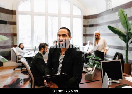 Portrait d'un homme souriant et confiant, conseiller financier assis avec un document au bureau Banque D'Images