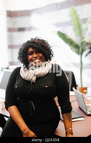 Portrait d'une femme d'affaires souriante penchée sur un bureau au bureau d'avocats Banque D'Images