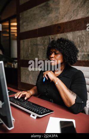 Femme d'affaires utilisant un ordinateur assis au bureau dans le bureau d'avocats Banque D'Images